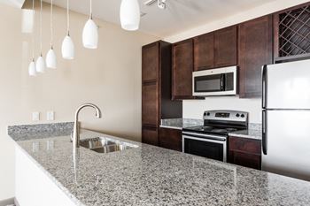 a kitchen with granite countertops and dark wood cabinets at Bella Vista Apartments, Indiana